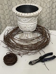 a white pot sitting on top of a table next to some scissors and twine