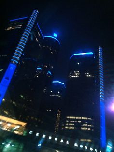 some very tall buildings lit up in the night sky with bright blue lights on them