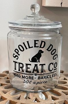 a dog treat jar sitting on top of a wooden table next to a white wall