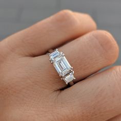 a woman's hand with a diamond ring on top of her finger and an engagement band in the middle