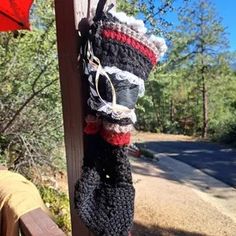 a pair of crocheted boots hanging from a wooden post