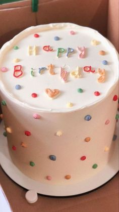 a birthday cake with white frosting and colorful sprinkles in a box