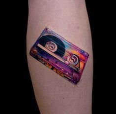 an old school style cassette tattoo on the right thigh, which is colored in rainbows