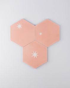 three pink hexagonals with white stars on them against a gray background,