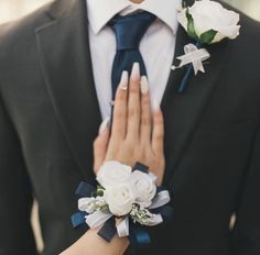 a close up of a person wearing a suit and tie with flowers on his lapel