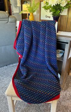 a blue and red blanket sitting on top of a wooden chair next to a table