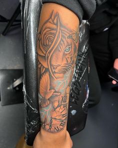 a man's arm with a tiger tattoo on it and a clock in the background