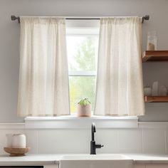 a kitchen sink under a window with curtains