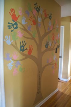 a tree painted on the wall with handprints in different colors and sizes, as well as hands