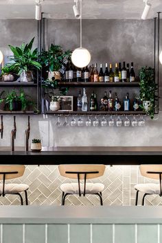 a bar with several bottles and glasses on the shelves, along with two stools