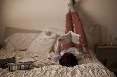 a person laying in bed reading a book