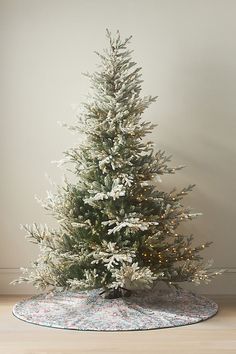 a white christmas tree on a rug in front of a wall