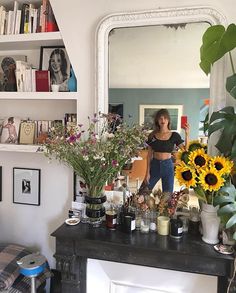 a woman taking a selfie in front of a mirror with sunflowers and other flowers