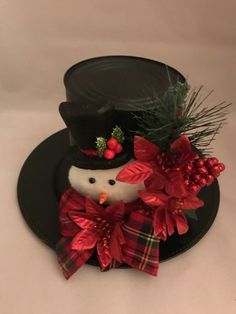 a black hat with a snowman on it and red poinsettis around the top