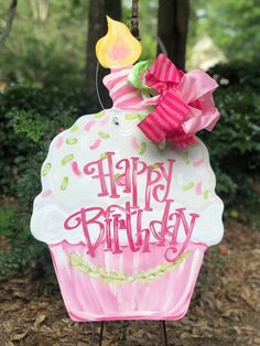 a happy birthday cupcake sign hanging from a tree