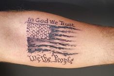 a man's arm with an american flag and the words in god we trust