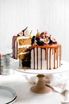 a cake sitting on top of a white plate covered in frosting and toppings