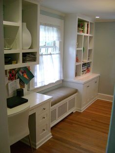 an empty room with white cabinets and shelves on the wall next to a wooden floor