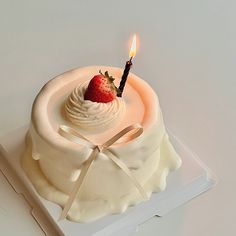 a white cake with a lit candle on top