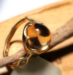 a gold ring sitting on top of a piece of wood next to a wooden stick