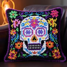 a decorative pillow with a colorful skull on it's side, sitting on a leather chair