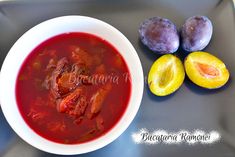 a white bowl filled with soup next to two plums