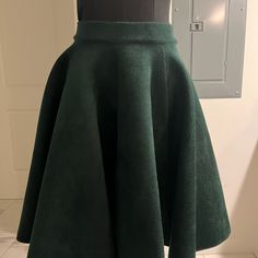 a green skirt on display in front of a white wall