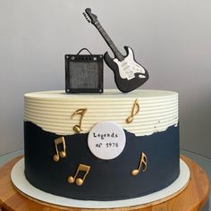 a birthday cake decorated with music notes and an electric guitar on top that reads legend's of 1970