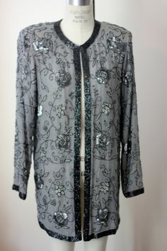 "A stunning Vintage Duster. This piece has no size tags, but it measures more like a small/medium. This is quite elegant and would be amazing for any special occasion. This piece is all silk with beading around the front and sleeves. There are also silver sequins that are throughout..Really unique and really a beauty! This is in Very good condition. I see only a few missing beads which is shown on image #8. It is a small area in the back that has a small strand of the patterned beading missing. Elegant Embellished Evening Outerwear, Elegant Embellished Fall Outerwear, Elegant Holiday Sequin Outerwear, Fall Wedding Embellished Outerwear, Glamorous Spring Wedding Outerwear, Elegant Embellished Outerwear For Party, Elegant Embellished Party Outerwear, Elegant Festive Outerwear For Celebrations, Fall Wedding Outerwear With Sequins