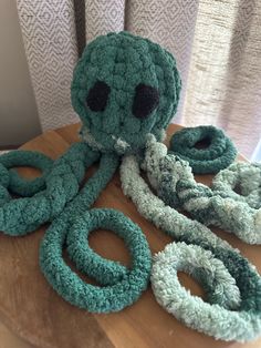 an octopus stuffed animal sitting on top of a wooden table next to two green rings