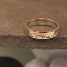 a gold wedding band with mountains on it