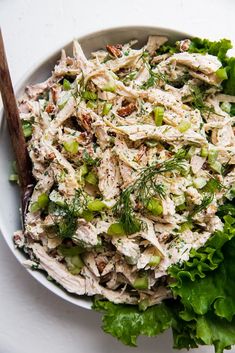 a white bowl filled with lettuce and chicken salad