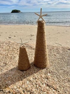 two small trees made out of rope and starfish on the sand at the beach