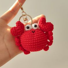 a hand holding a red crocheted crab keychain