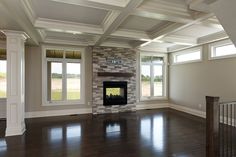 an empty living room with wood floors and white trimmings on the walls, windows, and a fireplace