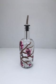 a glass bottle with pink flowers painted on it