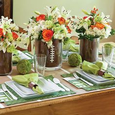 the table is set with green napkins and flowers in vases on top of each other