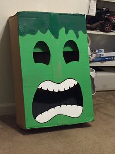 a cardboard box with a green monster face painted on it