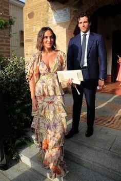 a man in a suit and tie standing next to a woman wearing a floral dress