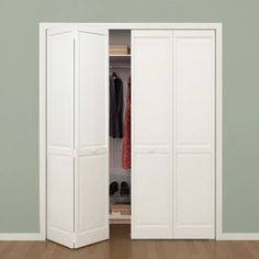 an open white closet with clothes hanging on hangers and shoes in the bottom drawer