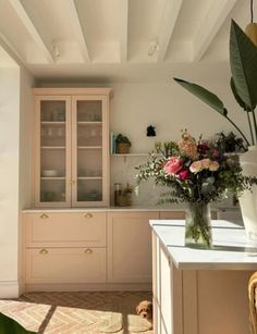 a vase filled with flowers sitting on top of a kitchen counter next to a window