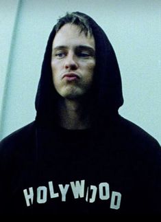 a man in a black hoodie is looking at the camera