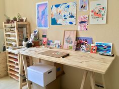 a wooden desk topped with lots of pictures next to a shelf filled with boxes and containers