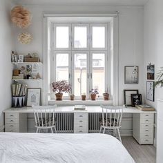 a bedroom with white walls and furniture in front of a large window filled with potted plants