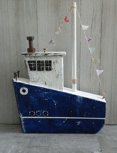 a blue and white boat sitting on top of a cement floor next to a wooden wall