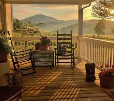 a porch with rocking chairs and potted plants on the back deck overlooking mountains in the distance