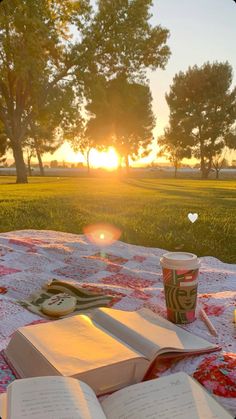 an open book sitting on top of a picnic table next to a cup of coffee