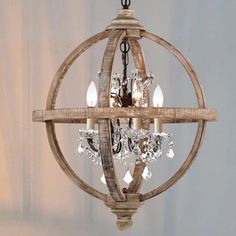 a wooden chandelier hanging from the ceiling with crystal drops on it's center