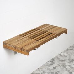 a wooden shelf mounted to the side of a white wall next to a tiled floor