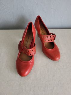 Vintage women`s classic red / apple red leather surface pumps with frontal decorative perforated strap (can`t open). Decorative buttons on the sides. Amazing, comfortable Mary jane style shoes with round toe and chunky, wooden pattern cone heels. EU size 38. GERMANY footwear. Rubber sole.  condition: great, a little bit used vintage. Without serious damages. Some slight scratches on the heels back. measurements: outsole length 27 cm / 10.5" in heels height 6,4 cm / 2.5" in bottom sole width in w Mary Jane Heels With Red Sole And Ankle Strap, Red Mary Jane Heels With Ankle Strap, Mary Jane Heels With Red Sole, Leather Mary Janes With 4-inch Heel And Round Toe, Mary Jane Heels With Red Sole And Round Toe, Red Mary Jane Heels With Block Heel, Red Mary Jane Block Heels, Red Closed Toe Mary Janes With Buckle Closure, Red Mary Janes With Buckle Closure And Round Toe